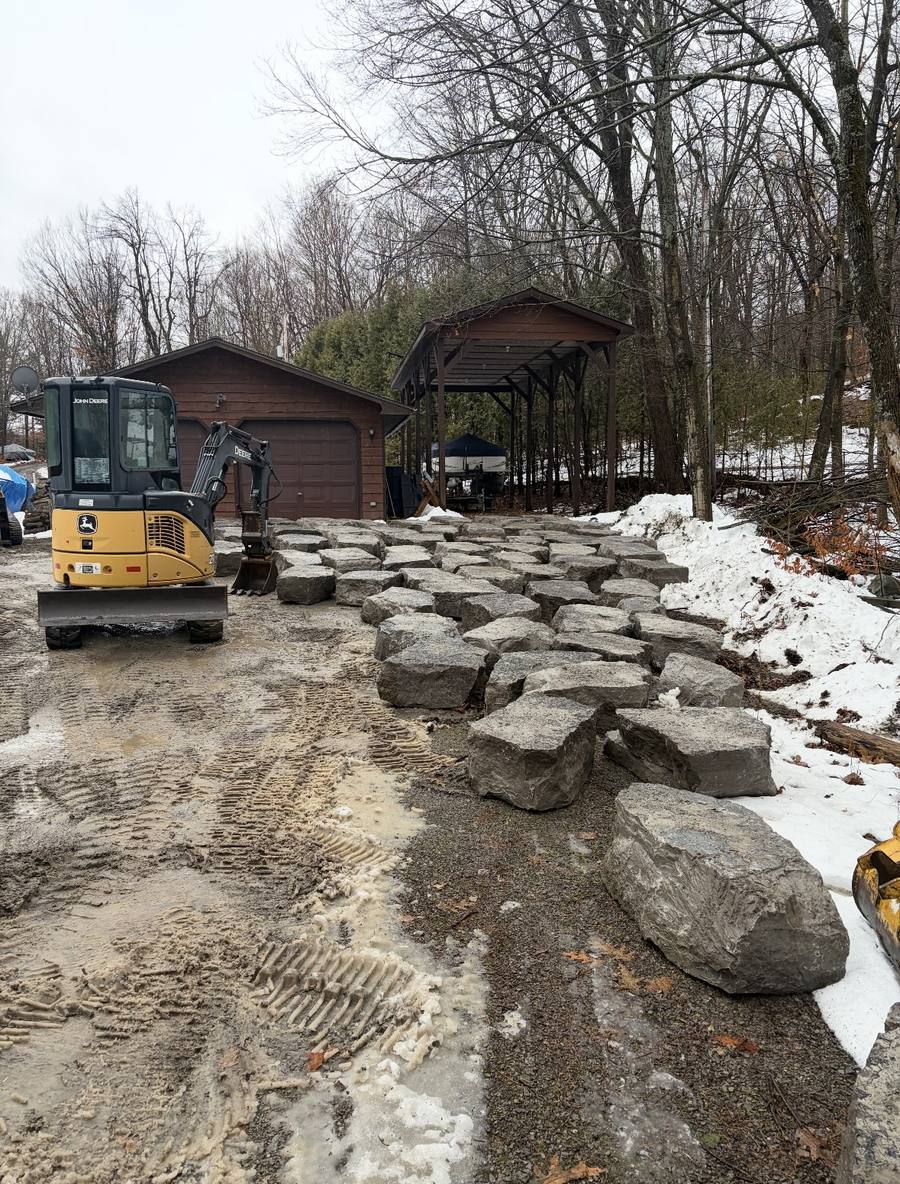 John Deere mini excavator placing large boulders for erosion control